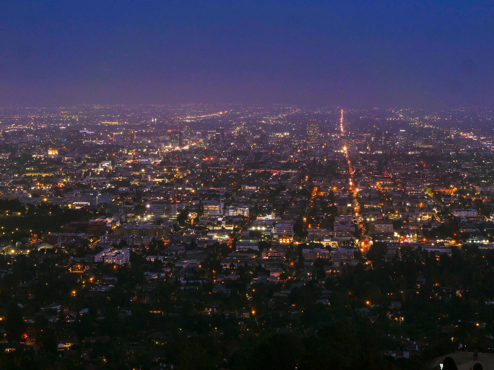 Wide aerial city view at night with glowing street lights below