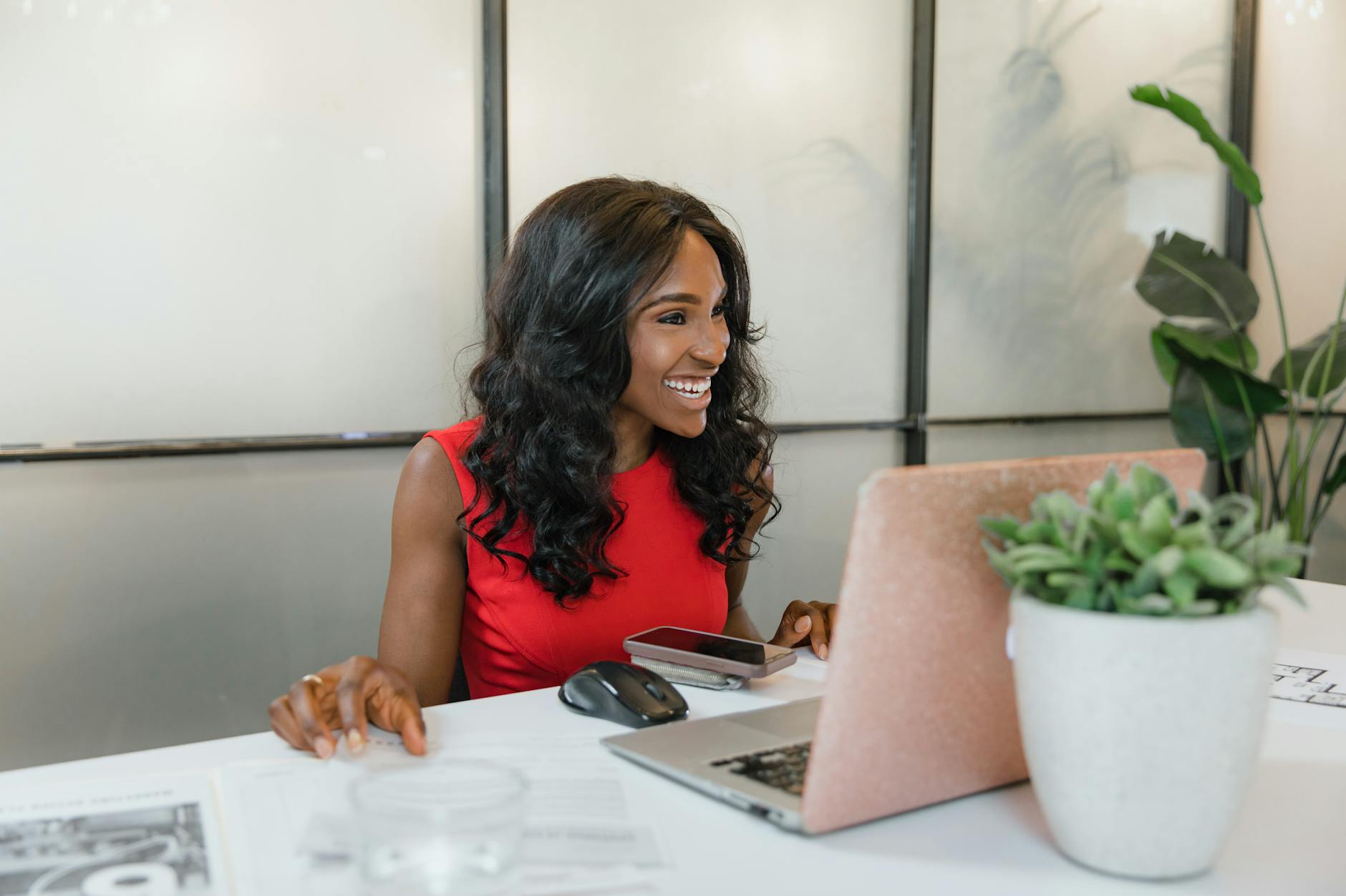 Small business owner smiling at laptop in bright modern office